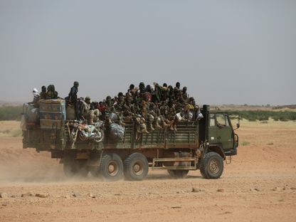 جنود من جيش النيجر يجلسون في الجزء الخلفي من شاحنة يرافقون النيجيريين المتجهين شمالًا نحو ليبيا أثناء مغادرتهم أغاديز، النيجر. 29 أكتوبر 2019 - REUTERS