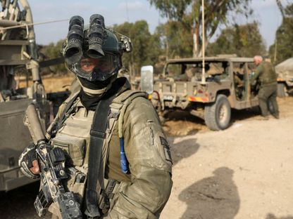 جندي إسرائيلي يقف بجانب مركبات عسكرية بالقرب من حدود إسرائيل مع غزة. 1 مايو 2024 - reuters