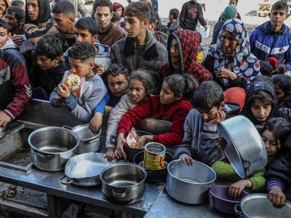 فلسطينيون يحملون أوعية فارغة انتظاراً للحصول على الطعام مع استمرار الهجمات الإسرائيلية في رفح، غزة. 26 يناير 2024 - AFP