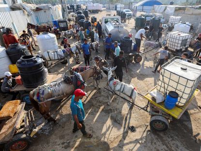 يتجمع فلسطينيون للحصول على المياه وسط النقص الحاصل، عند نقطة توزيع في دير البلح وسط قطاع غزة. 5 أغسطس 2025 - Reuters