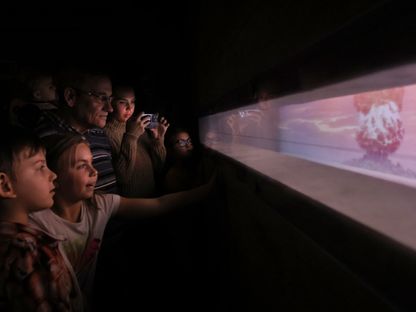 زوار يشاهدون مقطع فيديو لتجربة إسقاط قنبلة نووية أثناء زيارتهم لـ"جناح الذرة" في مركز معارض عموم روسيا في موسكو. 4 نوفمبر 2023 - AFP