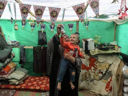 امرأة فلسطينية  تزين مع طفل خيمتها احتفالاً بشهر رمضان في رفح جنوب قطاع غزة. 09 مارس 2024 - AFP