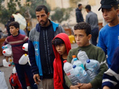 أطفال فلسطينيون يحملون زجاجات فارغة ينتظرون الماء وسط شح كبير، مدينة رفح، غزة. 5 ديسمبر 2023 - Reuters