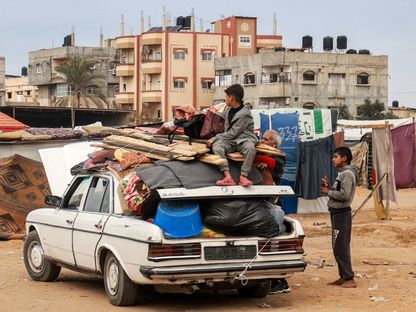 طفل يجلس فوق سيارة مكدسة بالأغراض مع فرار العديد من النازحين الفلسطينيين من رفح في اتجاه شمال القطاع في ظل تقارير عن قرب هجوم إسرائيلي في المنطقة الحدودية مع مصر. رفح، فلسطين. 13 فبراير 2024 - AFP