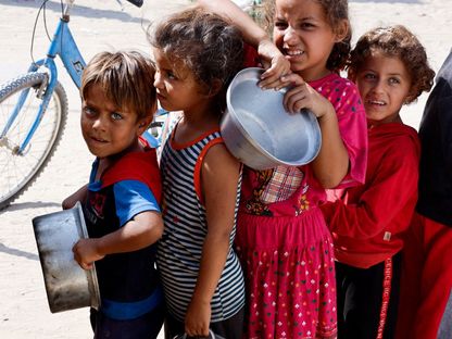 أطفال فلسطينيون يقفون في طابور للحصول على الطعام في مطبخ خيري في خان يونس جنوبي قطاع غزة. 16 أكتوبر 2024 - REUTERS