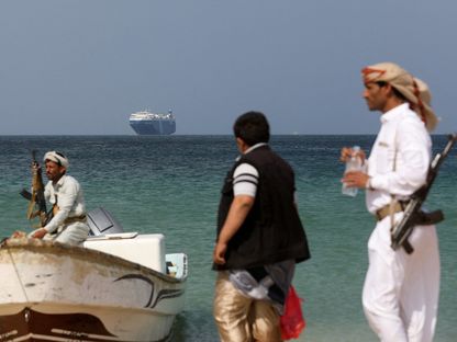 مسلحون وخلفهم السفينة جالاكسي ليدر التي سيطر عليها الحوثيون، ساحل اليمن. 5 ديسمبر 2023 - Reuters