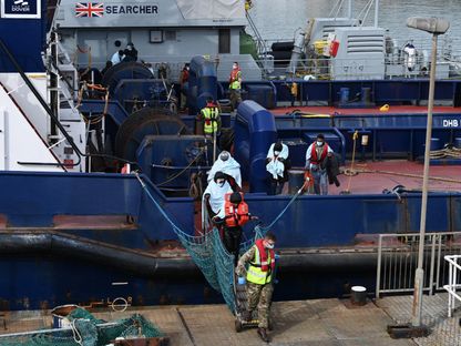 ضباط بريطانيون في ميناء دوفر يساعدون مهاجرين على النزول. 14 أبريل 2022 - AFP