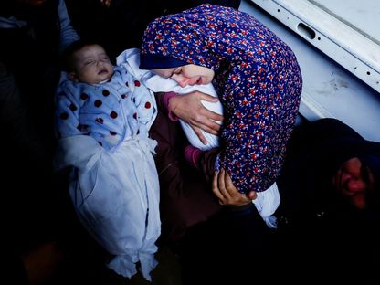 والدة التوأم الفلسطيني وسام ونعيم أبو عنزة تعانق الطفلين اللذين ولدا خلال حرب غزة وقتلتهما غارات إسرائيلية في رفح جنوب قطاع غزة. 3 مارس 2024 - Reuters