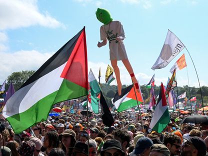 مشاركون في مهرجان جلاستونبري في مقاطعة سومرست جنوب غرب بريطانيا يحملون أعلاماً فلسطينية خلال عرض فرقة "نيكاب"- 28 يونيو 2025 - Reuters