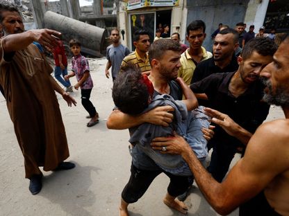 فلسطينيون يحملون أحد المصابين في غارة جوية إسرائيلية استهدفت مدينة غزة. 12 أغسطس 2025 - REUTERS