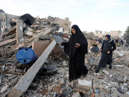 فلسطينيون يتفقدون أطلال منزل في دير البلح دمرته غارة إسرائيلية في وسط قطاع غزة. 15 يناير 2025 - Reuters