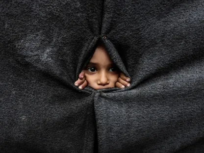 طفل فلسطيني نازح ينظر من بين الأغطية داخل مدرسة تديرها وكالة الأونرو في خان يونس بجنوب قطاع غزة. 9 أكتوبر 2025 - REUTERS