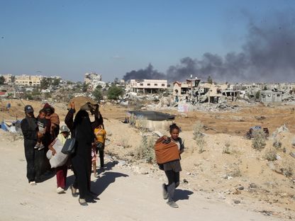 عائلة فلسطينية تغادر منطقتها بينما يتصاعد الدخان عقب غارة إسرائيلية على مبنى سكني في خان يونس جنوبي قطاع غزة- 16 أغسطس 2024 - Reuters