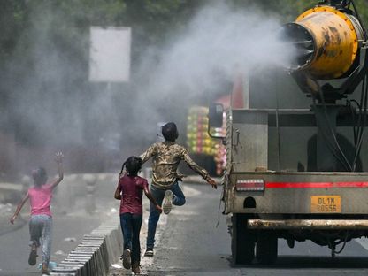 أطفال يركضون خلف شاحنة ترش المياه في يوم صيفي حار بالعاصمة الهندية نيودلهي. 10 يونيو 2024 - AFP