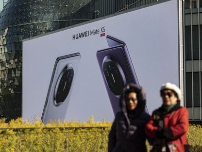 مشاة يمرون بجوار لافتة إعلانية كبيرة لهواتف "هواوي" في شنجهاي. - Bloomberg