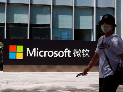 صينية تمر أمام شعار مايكروسوفت في مكتب الشركة بالعاصمة بكين. 4 أغسطس 2020 - REUTERS