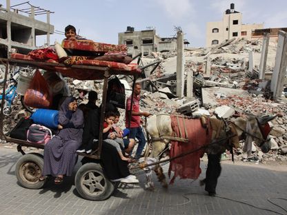 عائلة فلسطينية تنتقل مع بعض متعلقاتها بجوار حطام المنازل في بيت لاهيا شمال قطاع غزة. 19 مايو 2024 - AFP