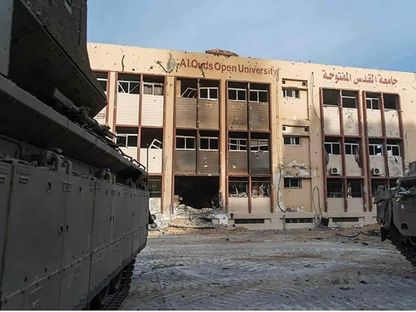 آثار القصف الإسرائيلي تظهر على أحد مباني جامعة القدس المفتوحة شمال غزة فيما تتوقف آليات عسكرية داخل الجامعة - facebook/Palestinian.MOHE