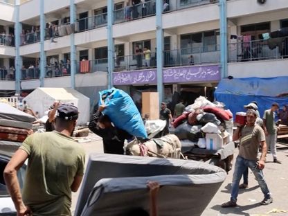 فلسطينيون يحاولون جمع متعلقاتهم قبل مغادرة مدرسة دير البلح التي كانت تؤويهم بعد تحذيرات إسرائيلية من قصف المدرسة. 16 أغسطس 2024 - Reuters