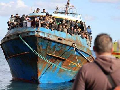 مهاجرون يقفون على متن قارب صيد في ميناء باليوخورا بعد عملية إنقاذ قبالة جزيرة كريت باليونان. 22 نوفمبر 2022 - Reuters