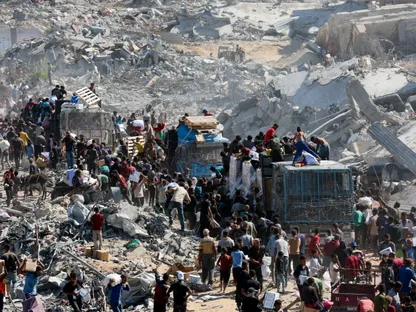 فلسطينيون يجمعون إمدادات المساعدات من الشاحنات التي دخلت غزة وسط وقف إطلاق النار بين إسرائيل وحركة حماس في خان يونس بجنوب قطاع غزة. 12 أكتوبر 2025 - Reuters
