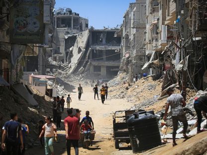 فلسطينيون في خان يونس جنوبي قطاع غزة بينما تبدو آثار الدمار الناجم عن الغارات الإسرائيلية المستمرة على القطاع. 11 يونيو 2024 - AFP