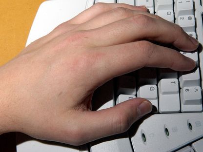 صورة تعبيرية لشخص يستخدم يده اليسرى في الكتابة على لوحة مفاتيح الكمبيوتر - Reuters