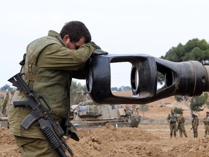 جندي إسرائيلي يضع رأسه على ماسورة مدفع بالقرب من الحدود مع غزة. 9 أكتوبر 2023 - AFP