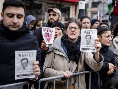 متظاهرون يحملون صور الرئيس الإسرائيلي يسحاق هرتسوغ ومكتوب عليها "مطلوب" في أمستردام. 10 مارس 2024 - AFP