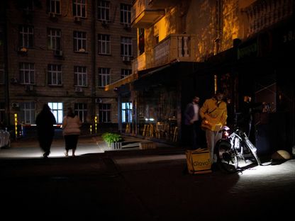 أشخاص يستخدمون المشاعل أثناء مغادرتهم أحد المتاجر الكبرى أثناء انقطاع جزئي للكهرباء في العاصمة الأوكرانية كييف وسط استمرار الغزو الروسي. 16 مايو 2024 - Reuters