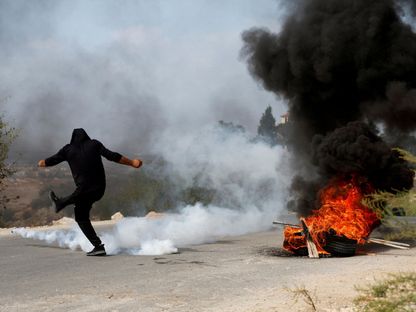 فلسطيني يركل قنبلة مسيلة للدموع خلال اقتحام القوات الإسرائيلية مخيم طولكرم. 5 أكتوبر 2023 - Reuters