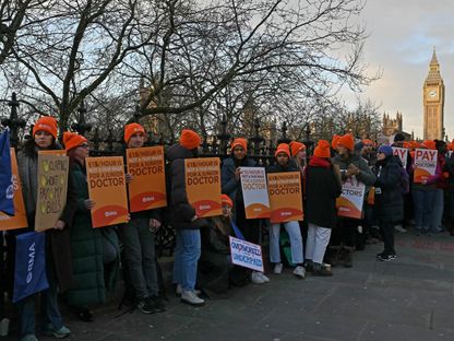 أطباء يحملون لافتات للمطالبة بأجور أفضل مع بدء إضراب مدته 6 أيام، خارج مستشفى بوسط لندن. 3 يناير 2024 - AFP