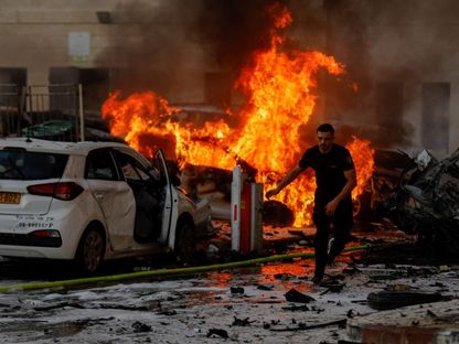 رجل يركض بعد اشتعال النيران في سيارة بعسقلان جنوب إسرائيل جرّاء صواريخ أطلقتها حركة "حماس" من قطاع غزة. 7 أكتوبر 2023 - Reuters