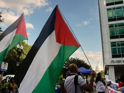 متظاهرون يحملون الأعلام الفلسطينية خلال احتجاج خارج مبنى يضم غرف أخبار قنوات تلفزيونية في واشنطن. 28 يوليو 2025 - reuters