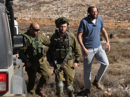 جنود إسرائيليون برفقة مستوطن قبالة قرية قصرة في نابلس، والتي قتل فيها مستوطنون مزارعاً فلسطينياً. 30 نوفمبر 2017 - AFP