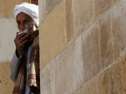 مُسن يدخّن سيجارة أمام منزله في القاهرة - REUTERS