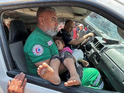 رجل يحمل طفلة بينما يقوم الفلسطينيون بإجلاء الجرحى من موقع غارة جوية إسرائيلية في مدينة غزة. 5 يونيو 2025 - Reuters