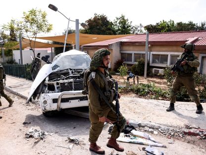 جنود إسرائيليون بجوار سيارة محطمة جراء هجوم لفصائل فلسطينية على بلدات ومدن في جنوب إسرائيل. 10 أكتوبر 2023 - Reuters