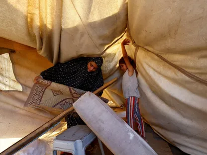 طفلة فلسطينية تساعد والدتها أثناء محاولتهما إصلاح خيمتهما التي تضررت بسبب الأمطار في وسط قطاع غزة. 16 نوفمبر 2025 - رويترز