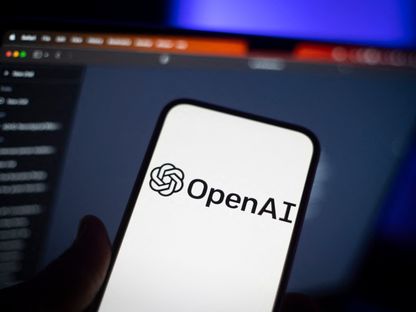 شعار شركة OpenAI على شاشة هاتف ذكي وفي خلفيته حاسوب شخصي من أبل في بولندا. 31 مايو 2023 - AFP