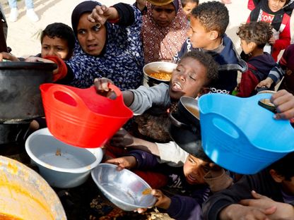 أطفال فلسطينيون يتجمعون لتلقي الطعام المطبوخ بواسطة مطبخ خيري خلال شهر رمضان في خان يونس بجنوب قطاع غزة،. 3 مارس 2025 - Reuters