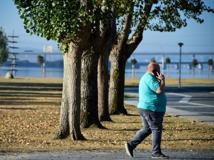 شخص يعاني من زيادة في الوزن يتحدث عبر الهاتف في حديقة بإسبانيا. 13 سبتمبر 2018 - AFP
