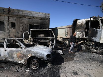 فلسطيني يتفقد الأضرار التي لحقت بمنزله ومركباته في قرية المغير بالقرب من رام الله في الضفة الغربية المحتلة. 13 أبريل 2024 - AFP