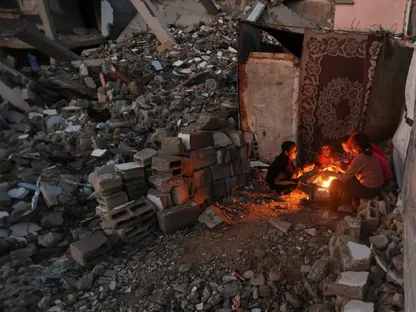 أطفال فلسطينيون يدفئون أيديهم على النار من البرد القارس في يوم ممطر بخان يونس جنوبي قطاع غزة. 25 نوفمبر 2025 - Reuters