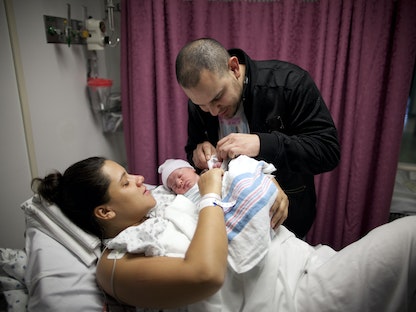 أميركيان ينظران إلى ابنتهما بعد ولادتها في مركز طبي بحي بروكلين في نيويورك. 31 أكتوبر 2011 - REUTERS