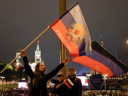 أشخاص يحملون أعلام مناطق دونيتسك ولوجانسك وخيرسون وزابوروجيا، بعد إعلان انضمامها إلى روسيا، يحتفلون بالميدان الأحمر وسط موسكو- 30 سبتمبر 2022 - REUTERS