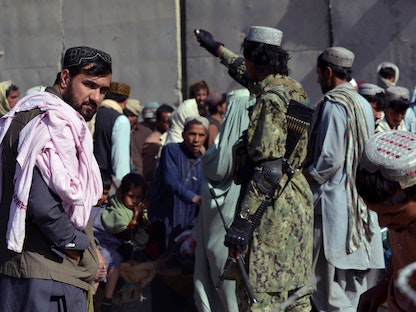 مقاتل من طالبان يشير إلى أشخاص ينتظرون العبور إلى باكستان عند نقطة العبور الحدودية بين البلدين في سبين بولداك، 3 نوفمبر 2021 - AFP