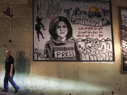 رجل يمشي أمام لوحة جدارية تصور الصحافية الفلسطينية الراحلة شيرين أبو عقلة في أحد شوارع بلدة أم الفحم في شمال إسرائيل- 5 سبتمبر 2022. - AFP