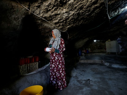 امرأة فلسطينية ترتب متعلقاتها بالكهف الذي تعيش فيه في مسافر يطا جنوبي الخليل بالضفة الغربية المحتلة - 7 مايو 2022 - REUTERS