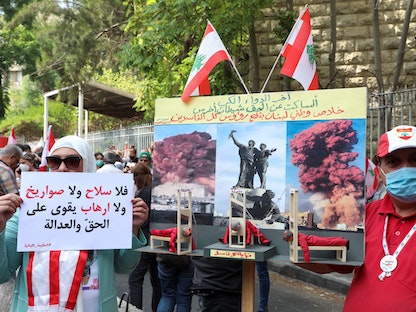 متظاهرون يرفعون لافتات وأعلاماً خلال تظاهرة أمام قصر العدل بعد تجميد تحقيق في انفجار مرفأ بيروت - 29 سبتمبر 2021 - REUTERS